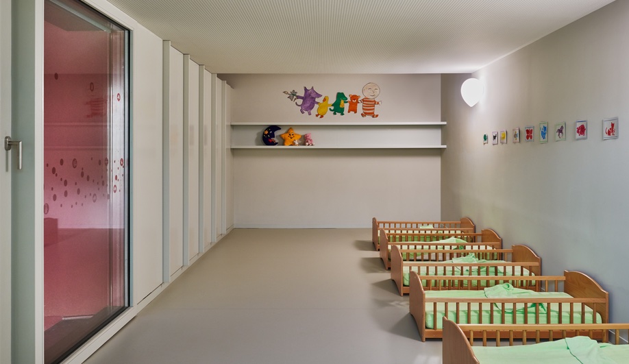 Nursery school design elevated: a napping room features pint-sized wood cots, with mint green bedding.