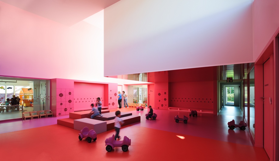 Nursery school design, elevated: a double-height hall in shades of pink.