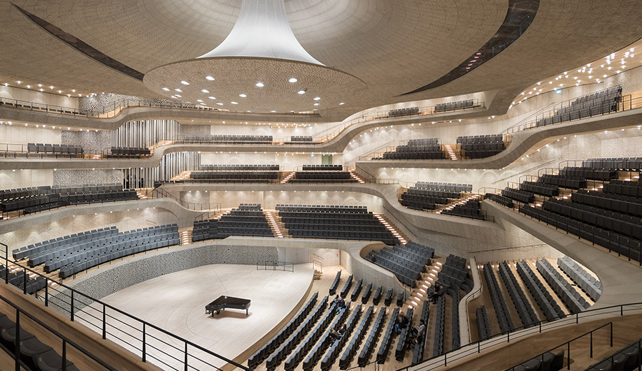 The firm compares the 2,100-seat Grand Hall, with its central peak, to a tent. The ceiling and walls are finished with engineered gypsum fibre panels sculpted into a scalloped pattern that scatters sound waves for superior acoustics. The organ was designed by Johannes Klais Orgelbau of Bonn; some of the largest of the organ’s 4,765 pipes (visible at centre-left) are placed where guests can walk alongside, and even touch them. The entire hall is structurally decoupled from the rest of the building for added soundproofing. 